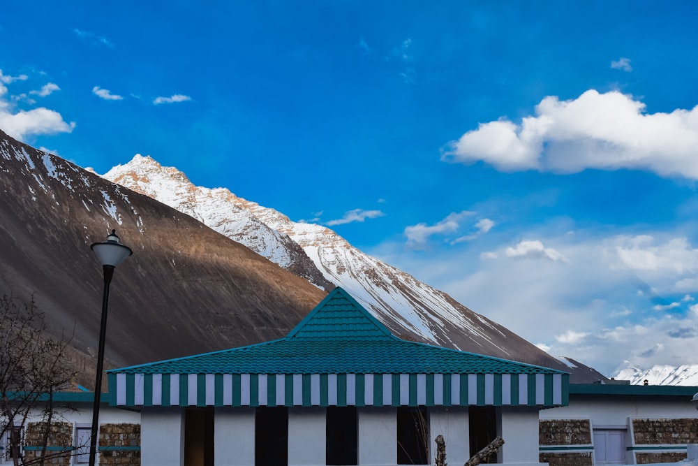 green and white wooden house near snow covered mountain during daytime