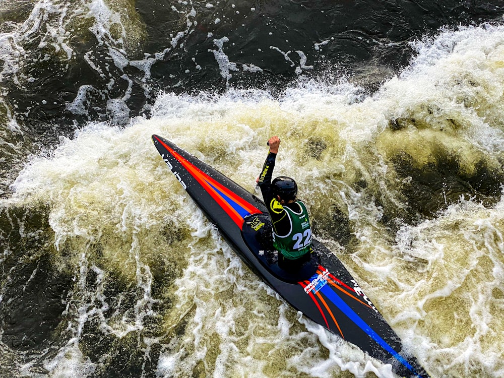 man in blue and red suit riding on blue and red kayak