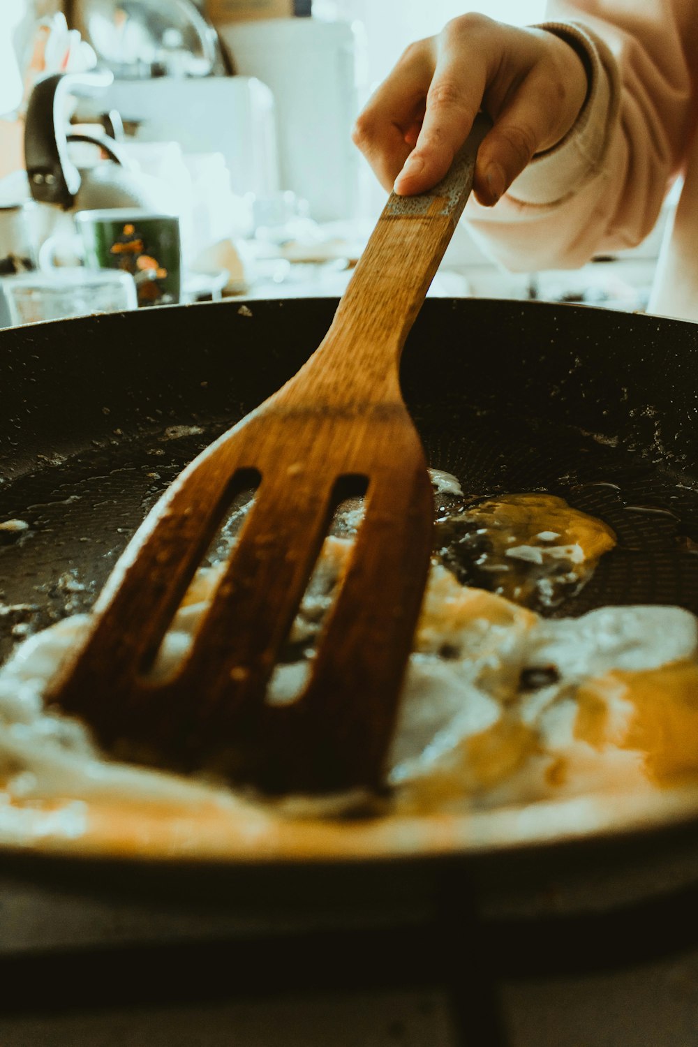 person holding brown wooden spatula