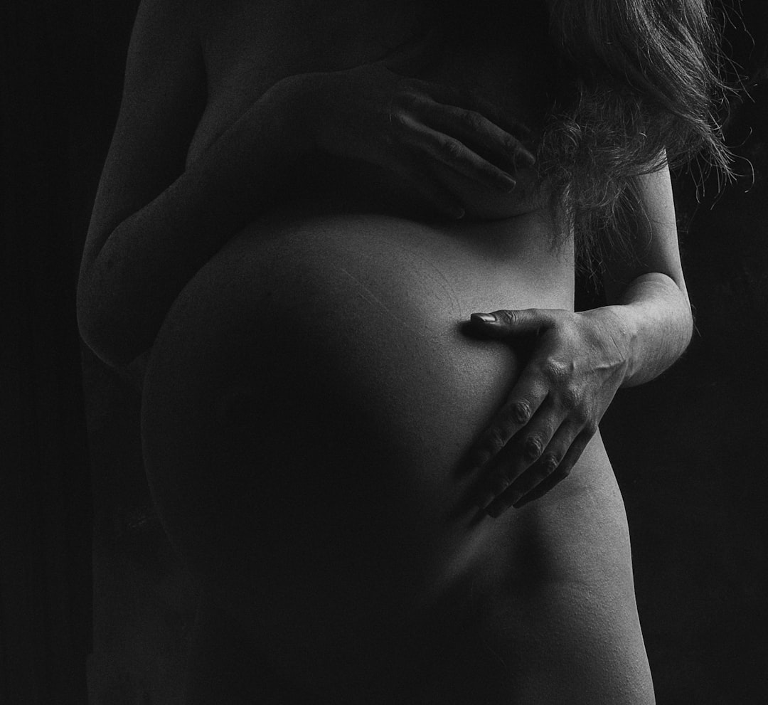 grayscale photo of woman covering her breast