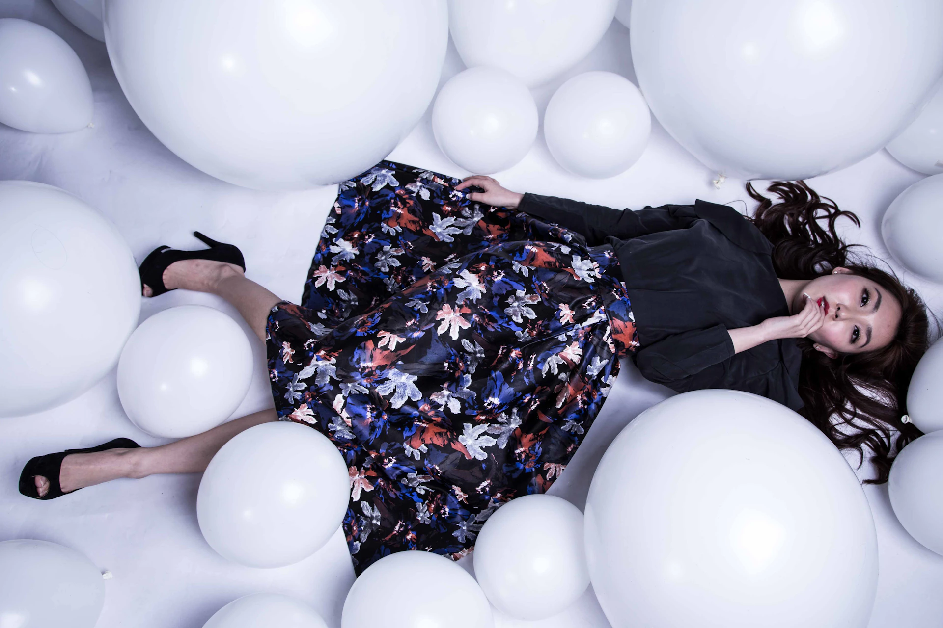 woman in blue red and white floral dress shirt standing beside white balloons