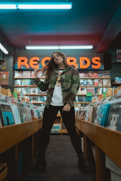 woman in green jacket standing near brown wooden shelf