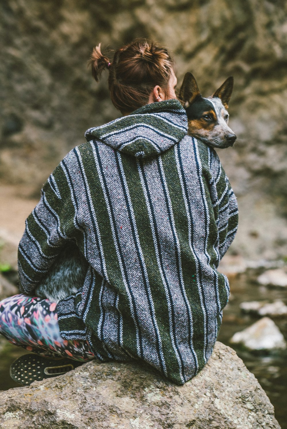 woman in black and white striped sweater holding black and white short coat small dog