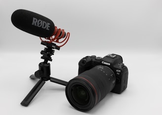 A Canon EOS R6 camera paired with a RØDE microphone is mounted on a compact tripod. The setup likely indicates use for video or audio recording purposes.