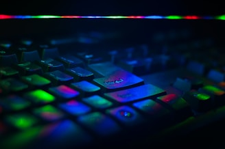 Close-up of hands typing on a keyboard with colorful AI-themed graphics glowing on the screen.