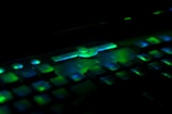 Close-up of a vintage keyboard with green backlit keys on a black background.