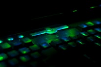 Close-up of hands typing on a minimalist keyboard with green ambient lighting reflecting the brand colors.