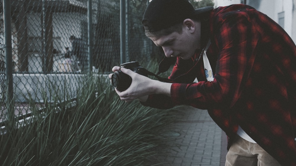 man in red jacket holding black smartphone