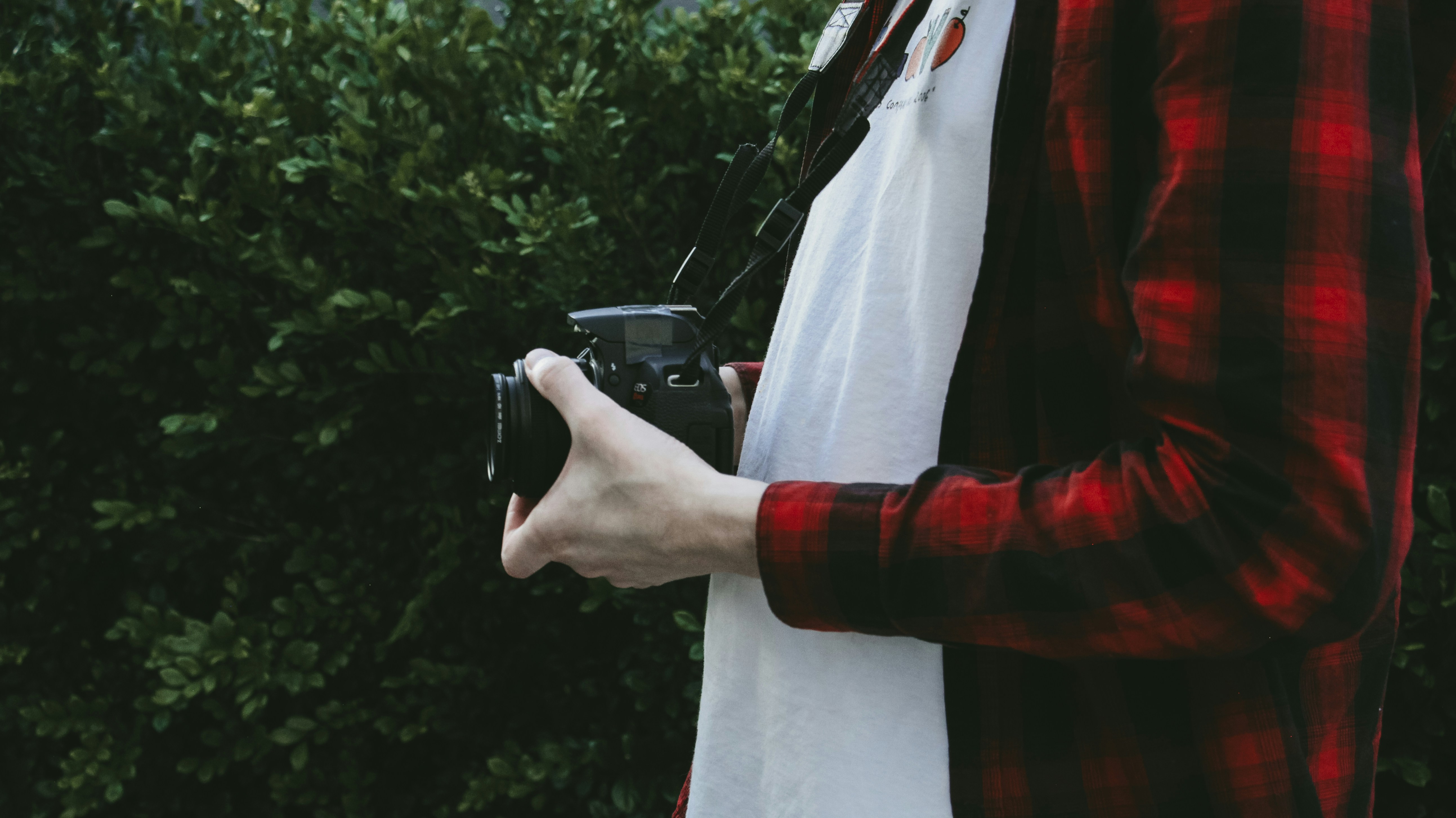 man in red jacket holding black dslr camera