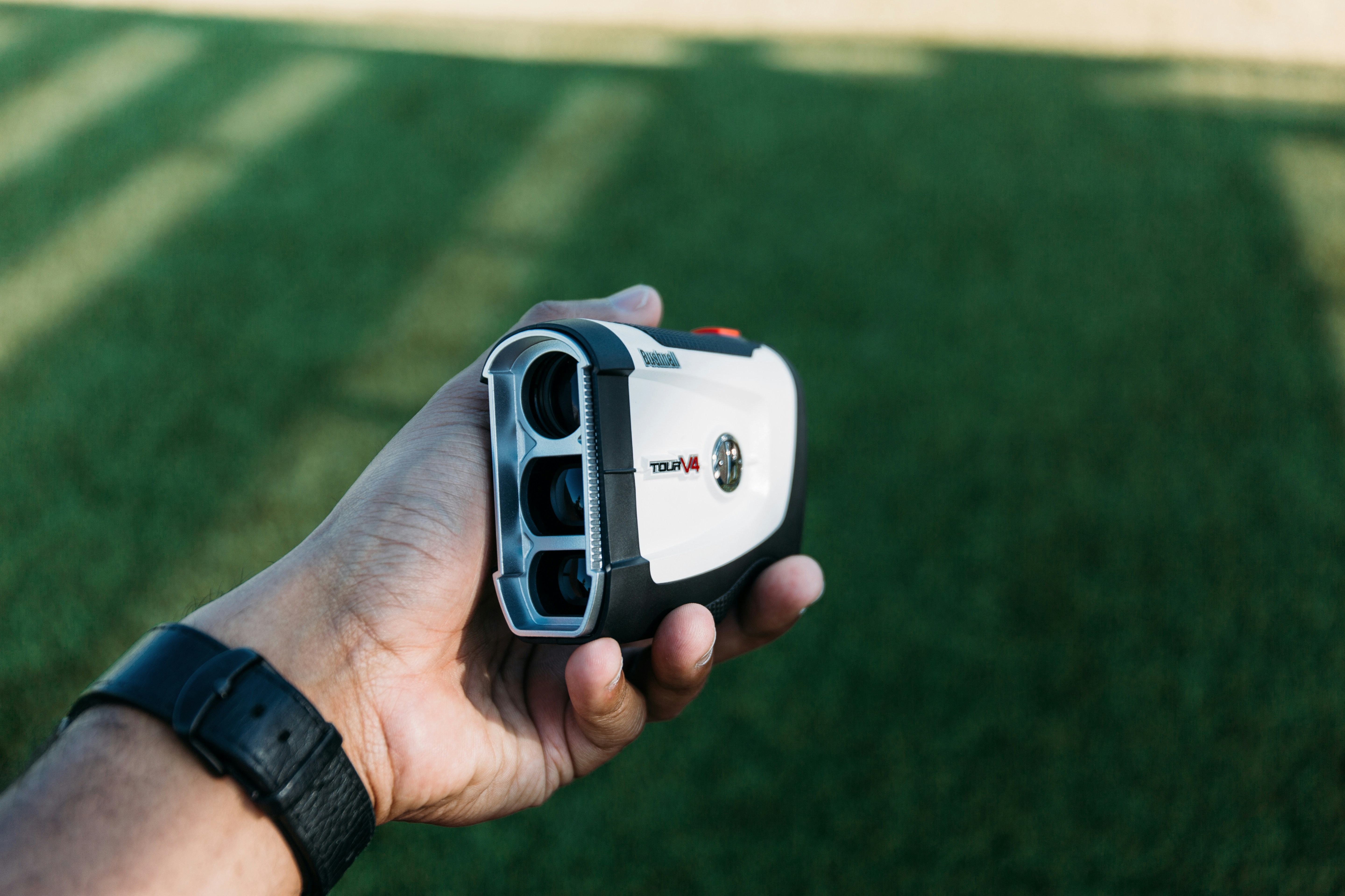 Hand holding golf range finder in daytime