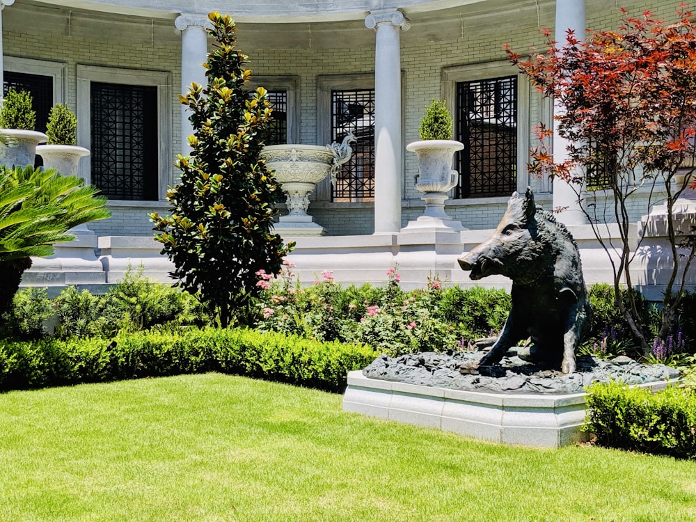 Schwarze Statue auf grünem Grasfeld in der Nähe eines weißen Betongebäudes tagsüber