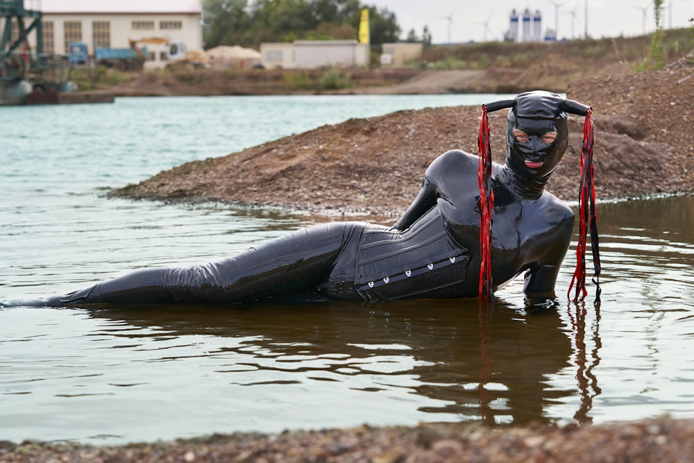 Un hombre con un traje de neopreno flotando en un cuerpo de agua
