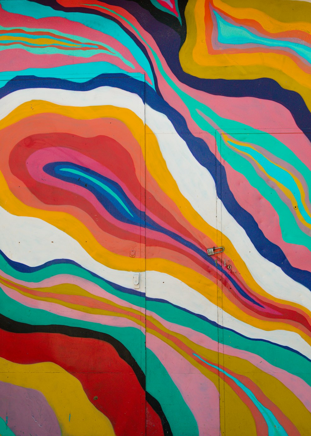 uma pintura de uma onda multicolorida ao lado de um edifício