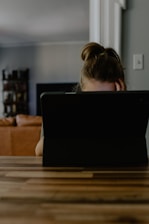 woman in white tank top sitting on chair using black laptop computer