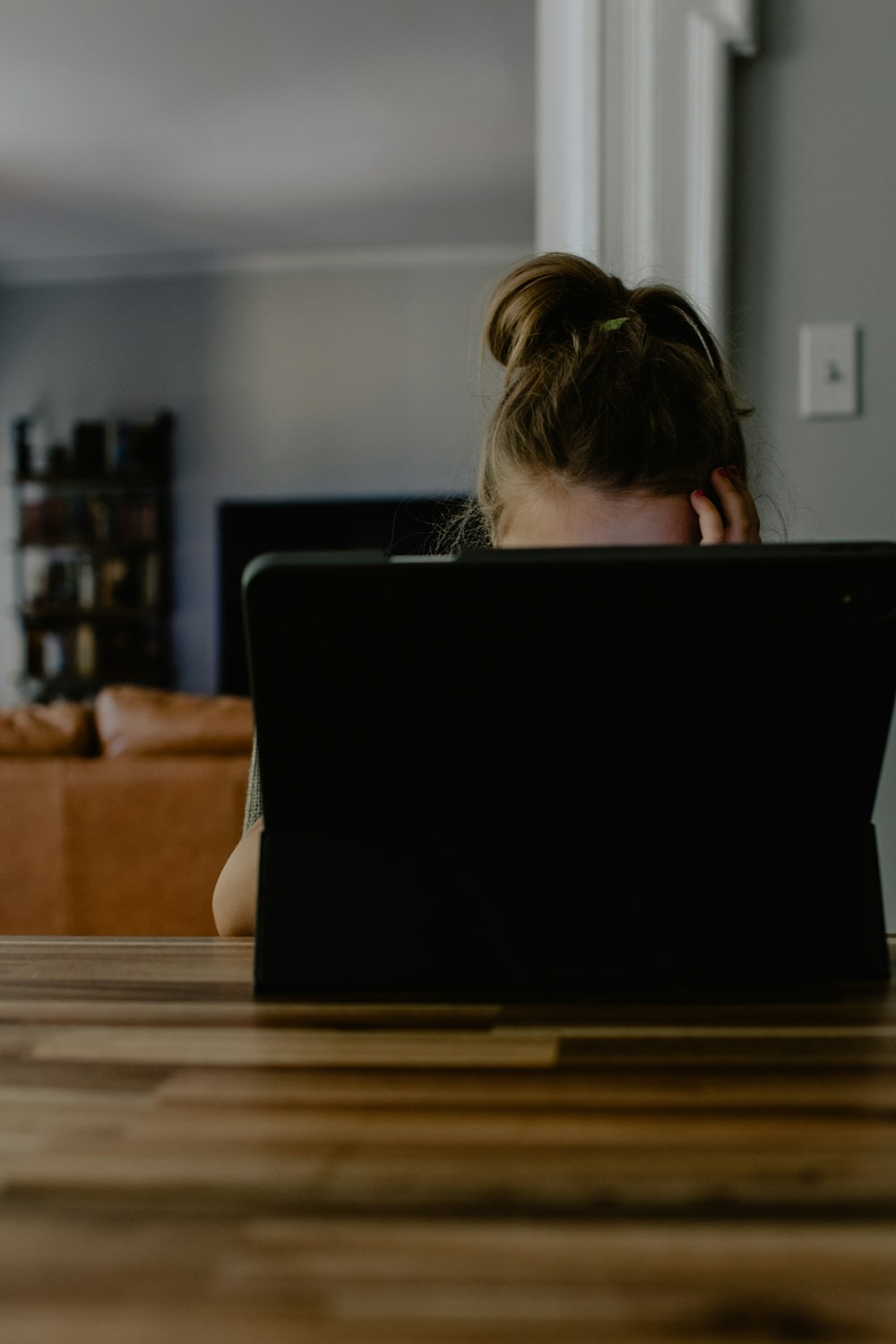 woman in white tank top sitting on chair using black laptop computer