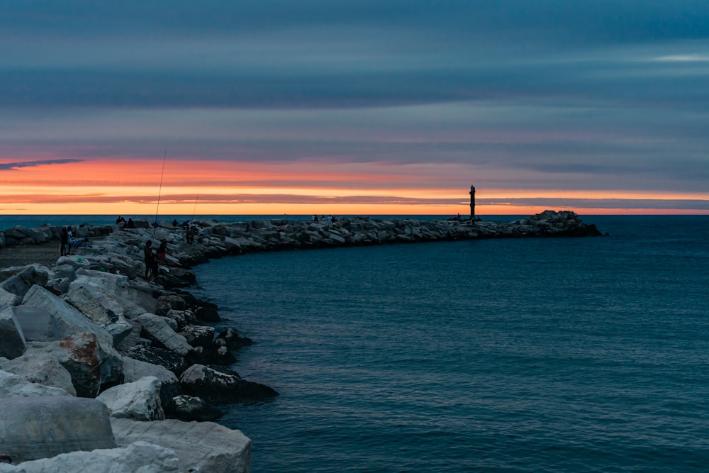 gray rocks on sea shore during sunset