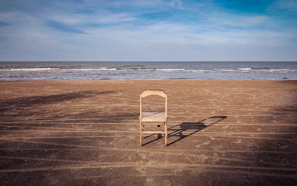 white and brown wooden chair on beach shore during daytime