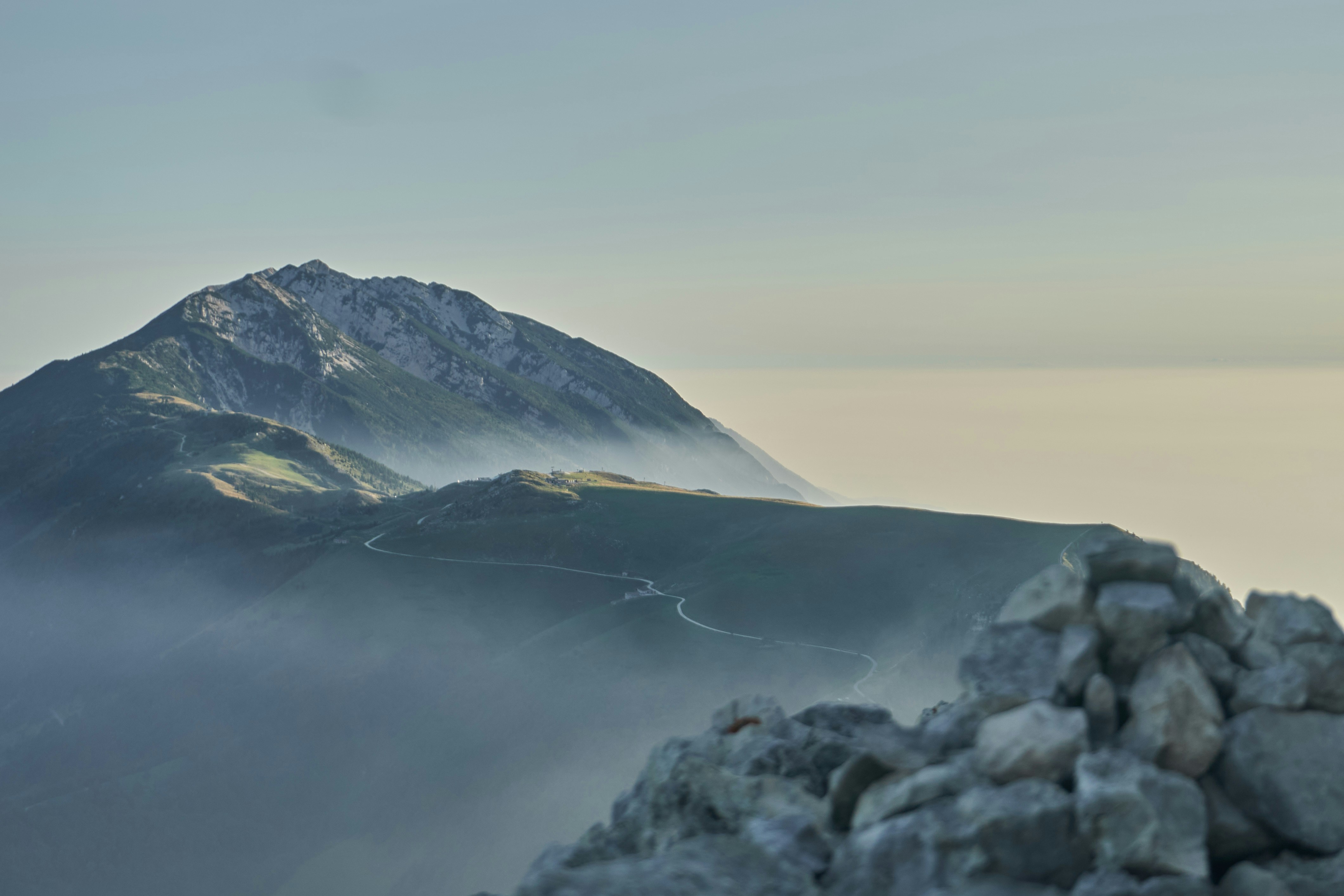 Rocky mountain peak with grassy slopes and misty haze.