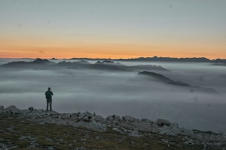 A candid photo of a traveler standing on a mountain ridge at sunrise, overlooking a misty valley.