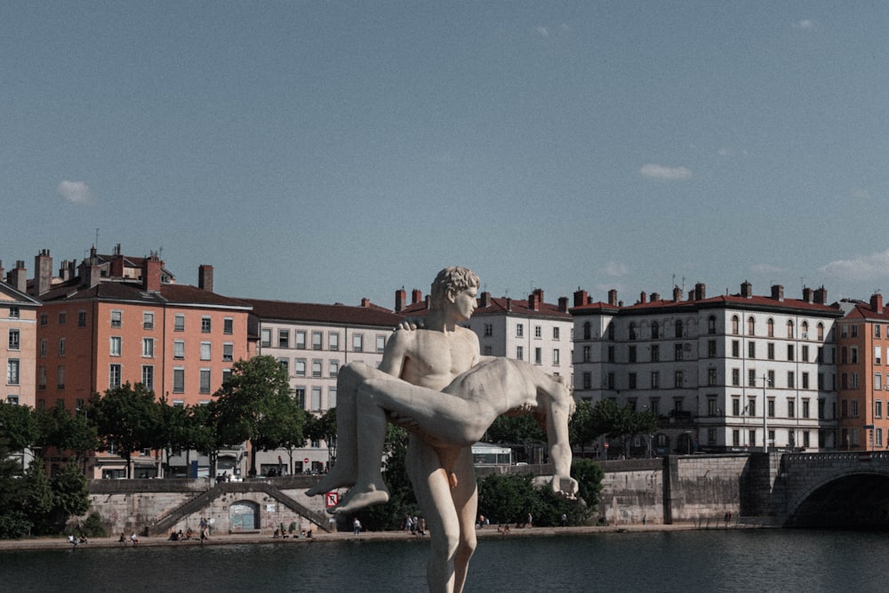 mulher na estátua branca do vestido perto do corpo de água durante o dia