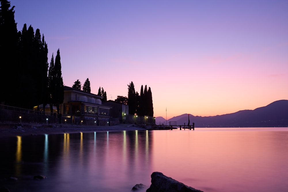 silhouette of building near body of water during sunset