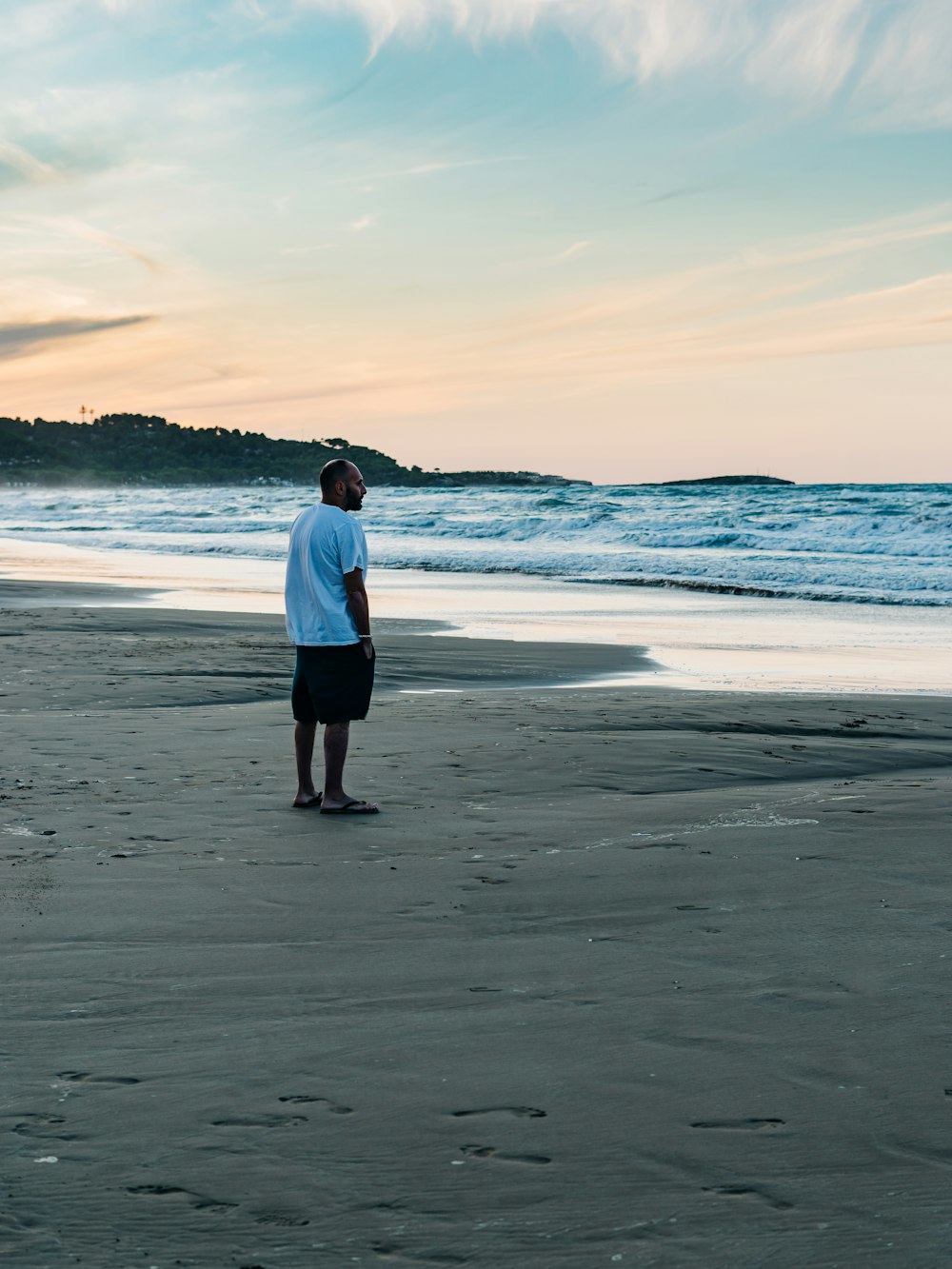 Homme en chemise blanche debout sur la plage pendant la journée