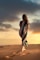 woman in black and green striped dress standing on brown sand during sunset