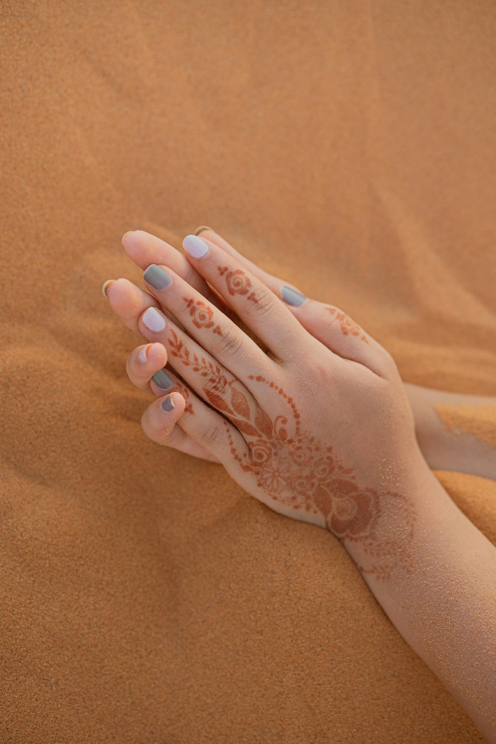 person with white manicure on brown textile
