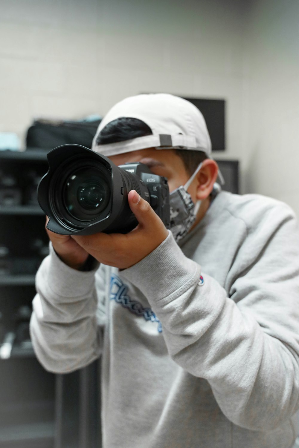 man in gray hoodie holding black dslr camera