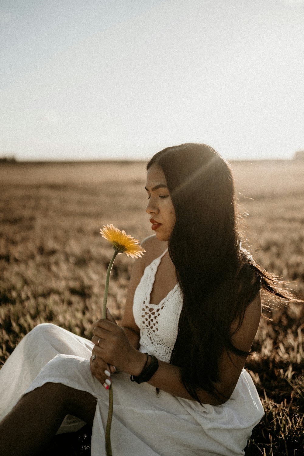 woman in white and black polka dot tank top holding yellow flower