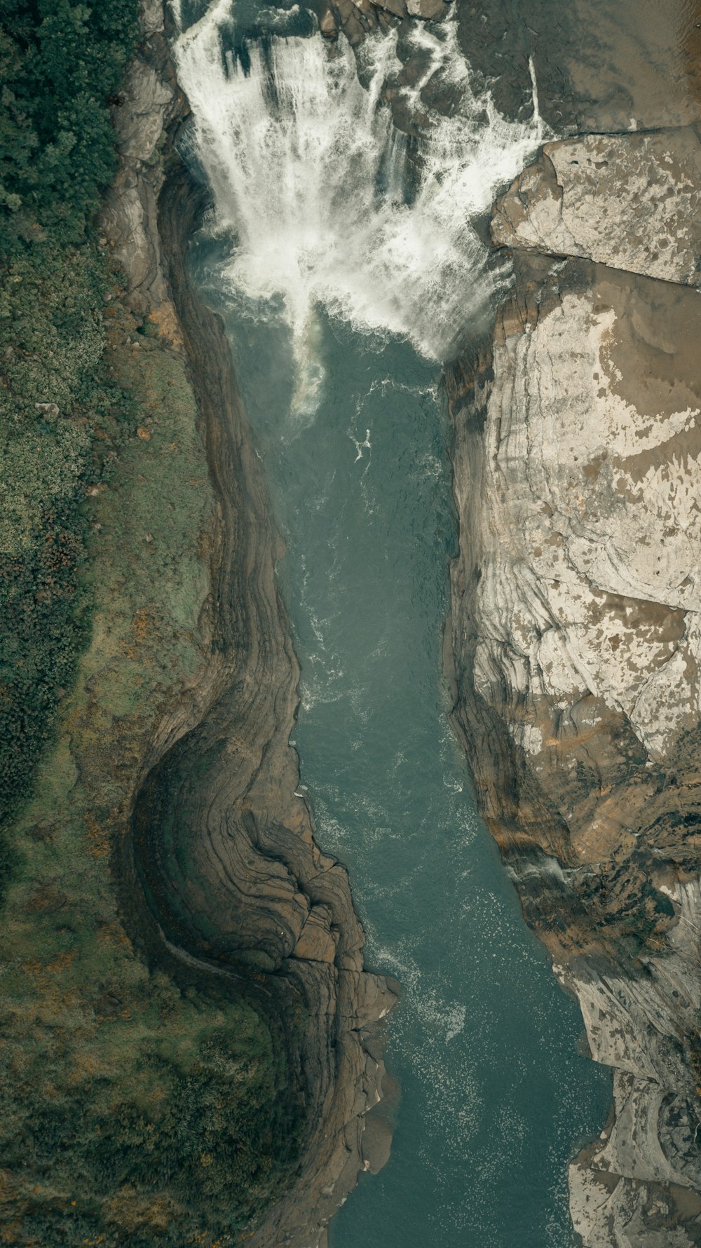 water falls between brown rocky mountain during daytime