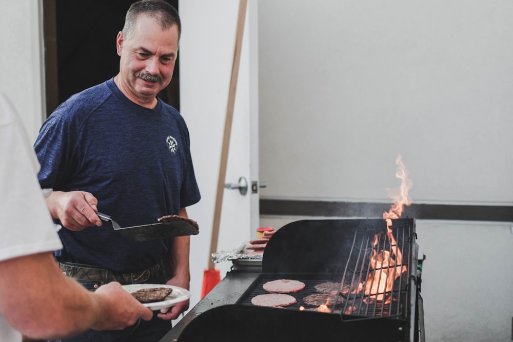 Un uomo sta cucinando hamburger su una griglia