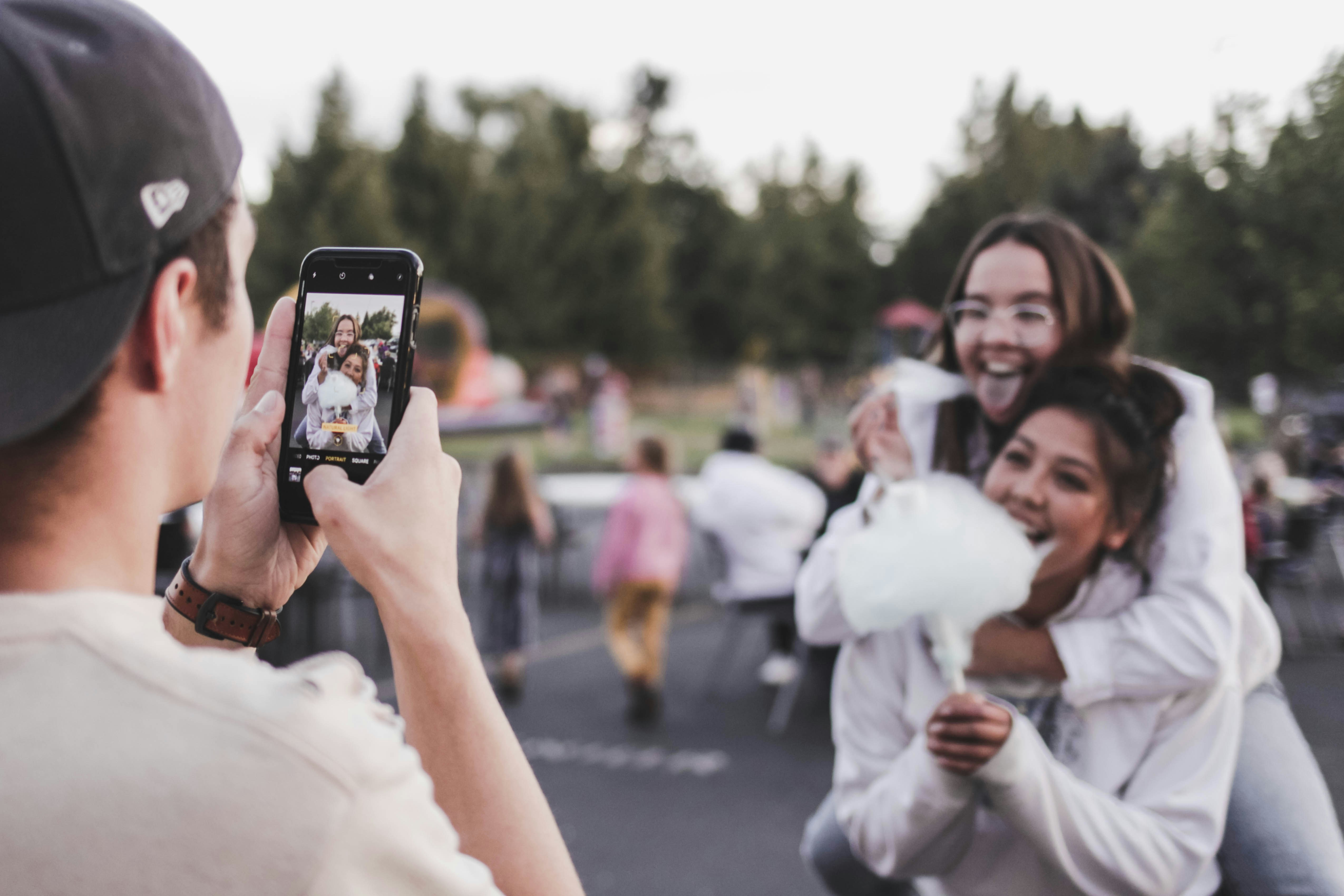 Man taking picture of two girls eating cotton candy