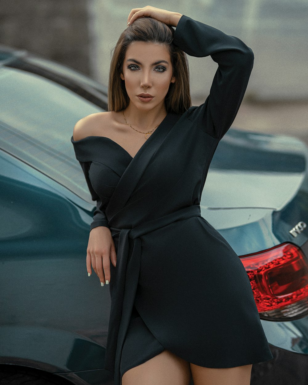 Frau im schwarzen Langarmkleid steht neben rotem Auto