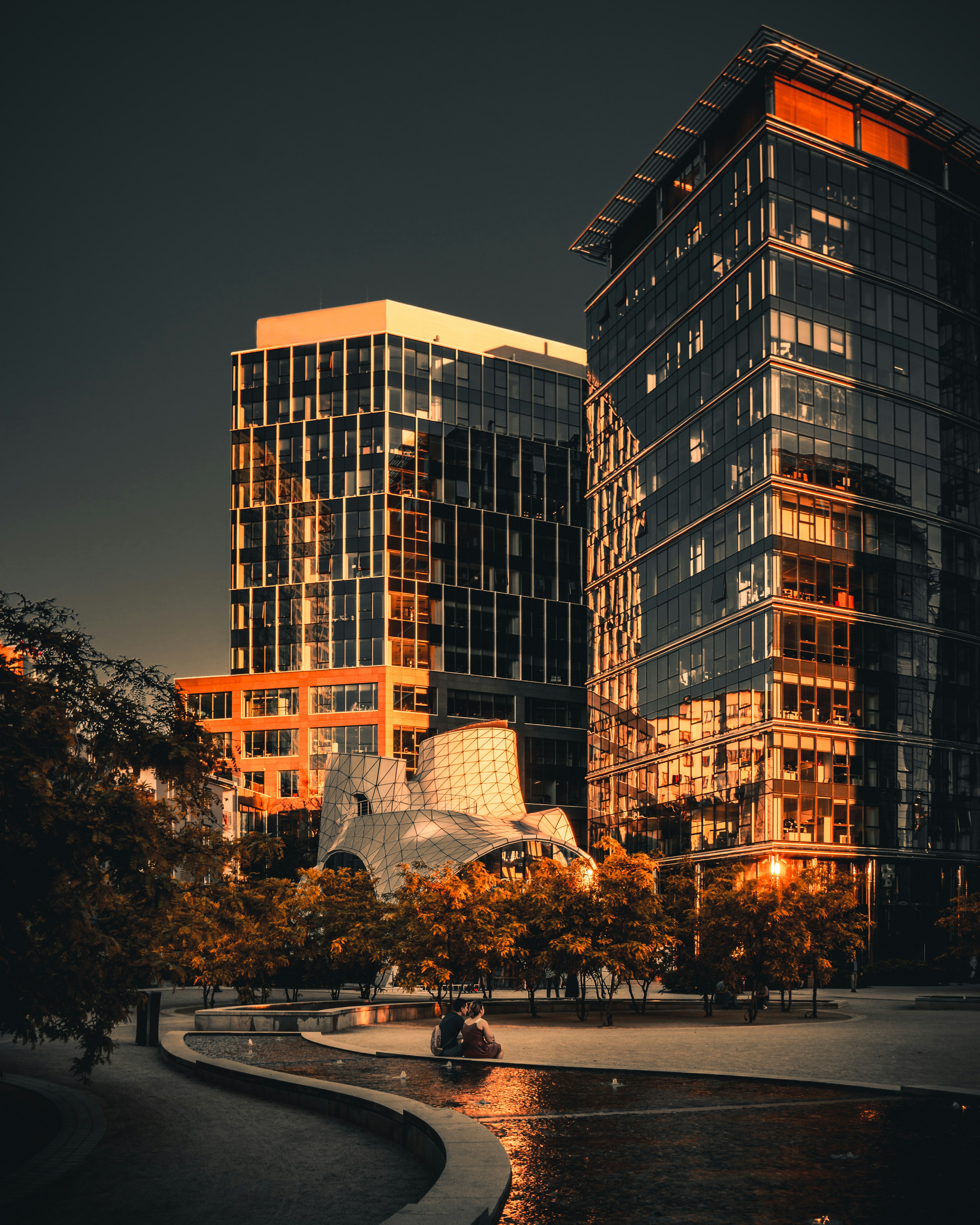 people walking on sidewalk near high rise building during night time