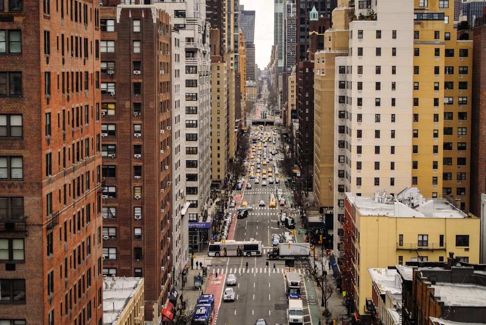 cars on road between high rise buildings during daytime