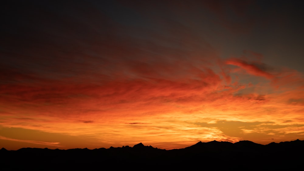 silhouette of mountain under orange and blue sky