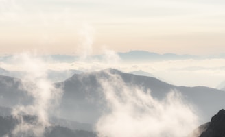 A serene landscape shot of misty mountains at dawn with soft pastel skies.