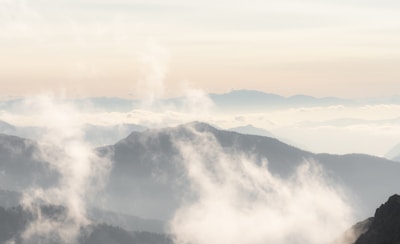 A serene landscape of misty mountains at dawn with soft pastel hues.