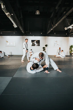 man in white long sleeve shirt and black pants sitting on black floor