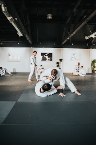 man in white long sleeve shirt and black pants sitting on black floor
