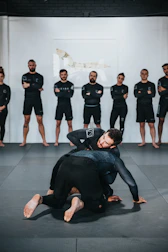 group of people in black shirts and black pants doing yoga