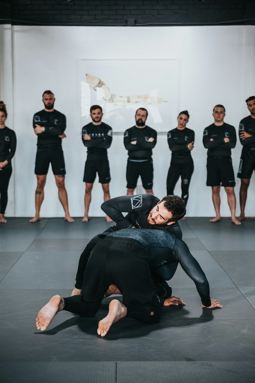 group of people in black shirts and black pants doing yoga