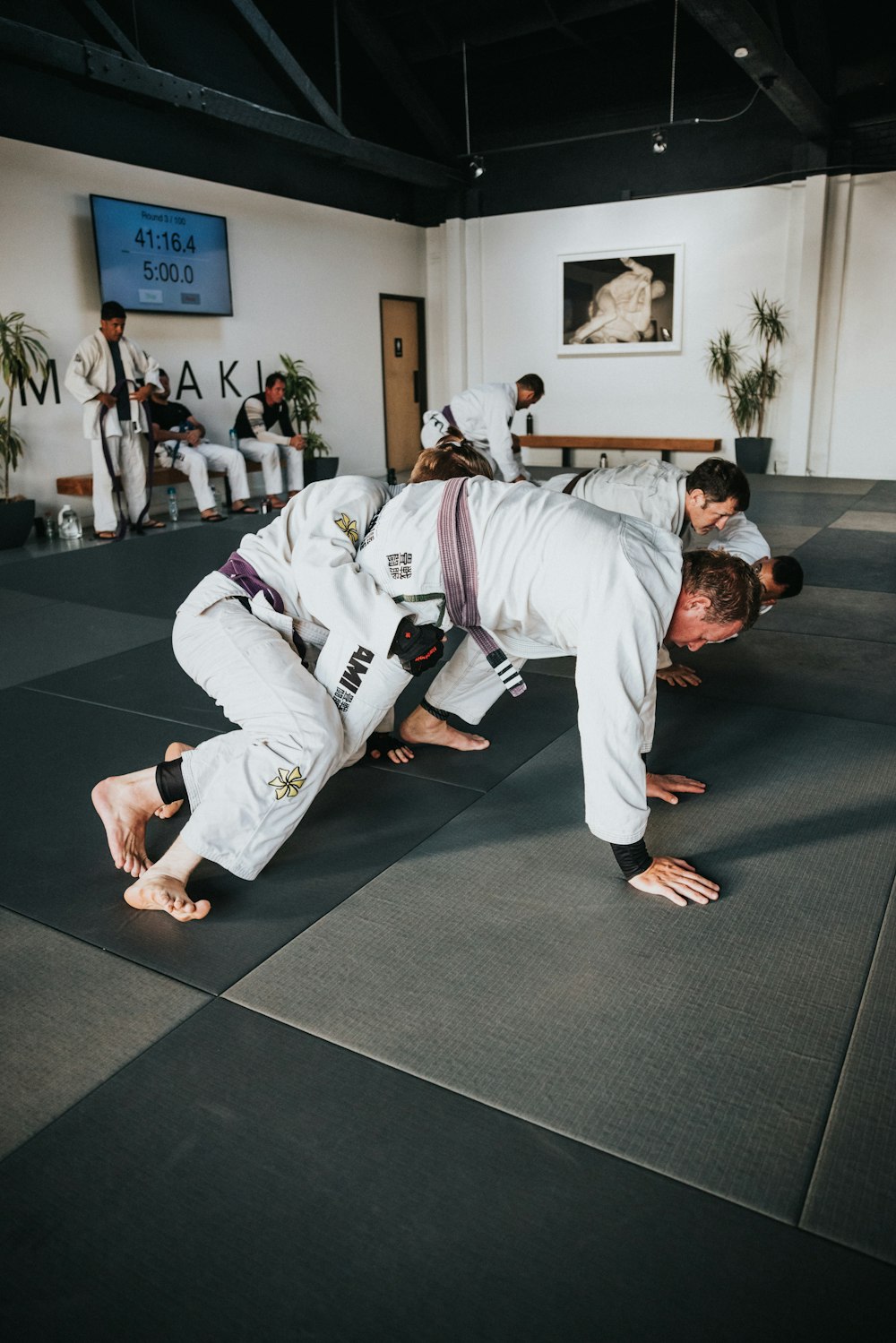 Hombre en Karate Gi blanco arrodillado sobre alfombra negra