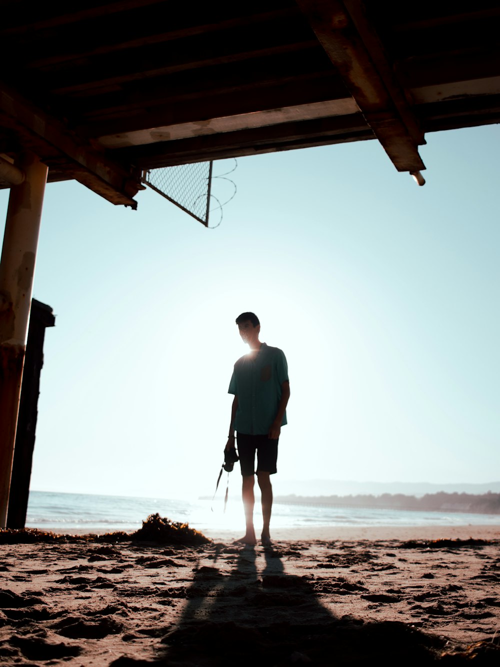 man in white t-shirt and black shorts standing on beach during daytime