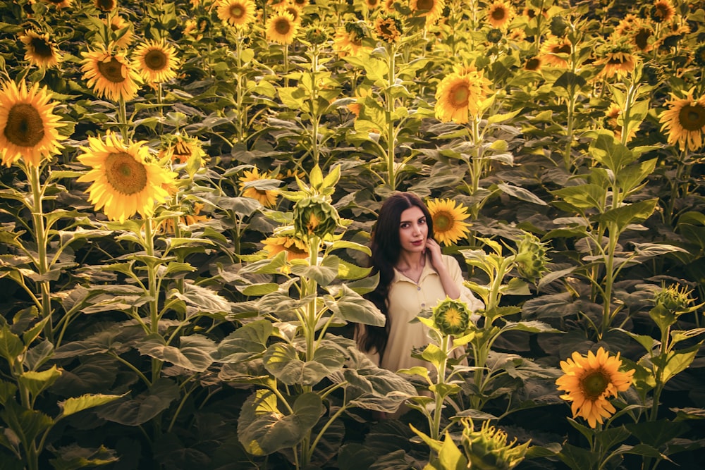 woman in white dress standing on sunflower field during daytime