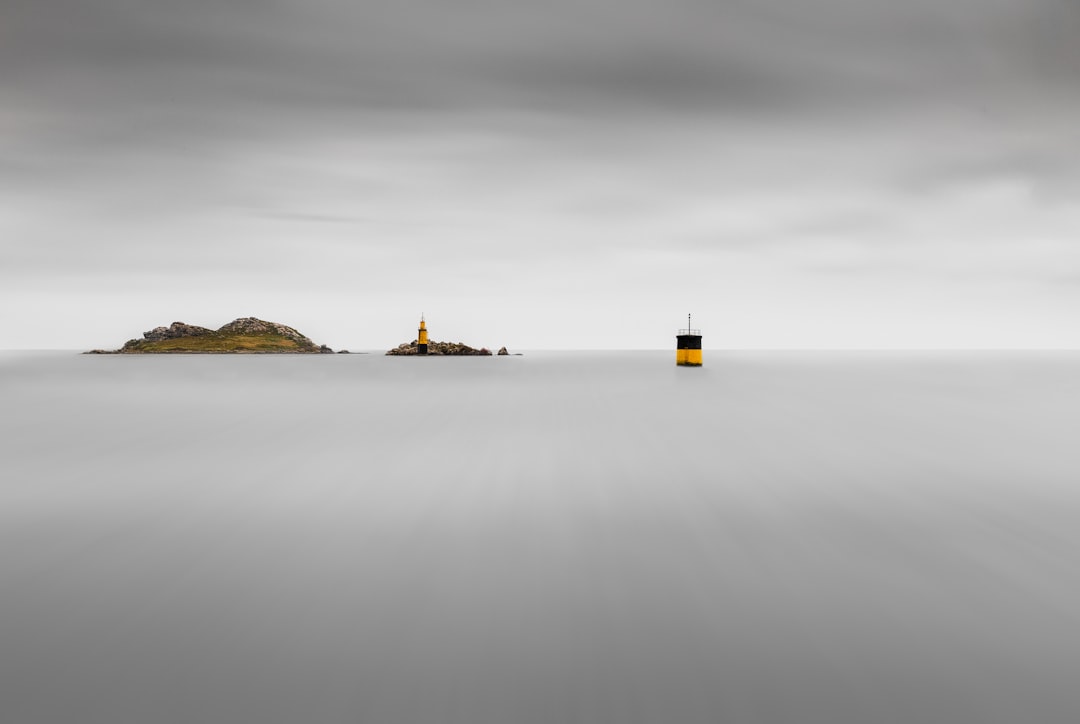 yellow and black lighthouse on top of hill