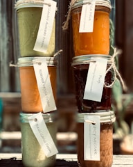 Colorful jars of natural herbal creams lined up on a wooden shelf.