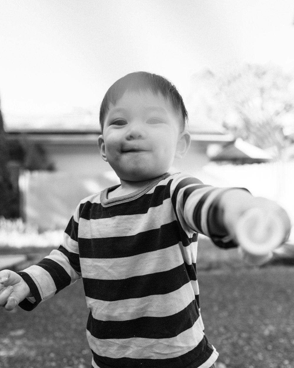 grayscale photo of baby in striped shirt
