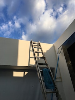 A ladder leaning against a house with a chimney sweep at the top